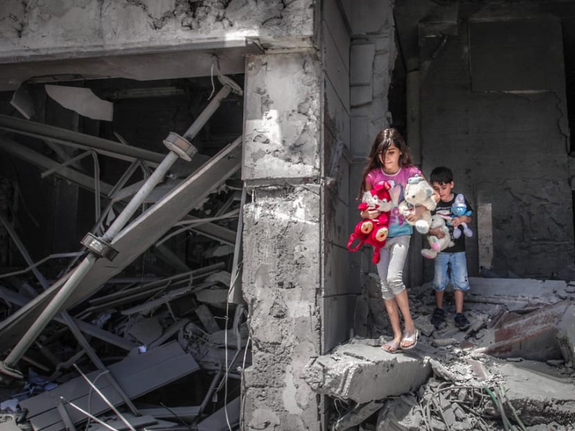 Palestinian children salvage toys from their home at the Al-Jawhara Tower in Gaza City's Rimal neighbourhood, on May 17, 2021, which was heavily damaged in Israeli airstrikes.