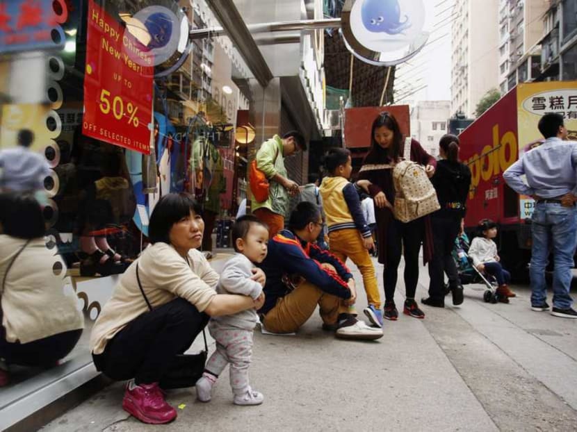 Mainland Chinese visitors rest outside a shop at a shopping district in Hong Kong on February 24, 2015. Photo: Reuters