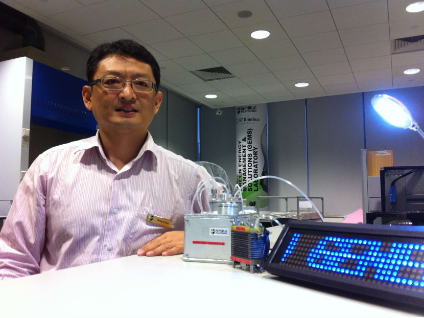 Republic Polytechnic senior academic staff Dr Wang Yihua with the fuel cell system he developed with his team. Electricity generated from the system is powering the table lamp and LED signboard. Photo: Neo Chai Chin