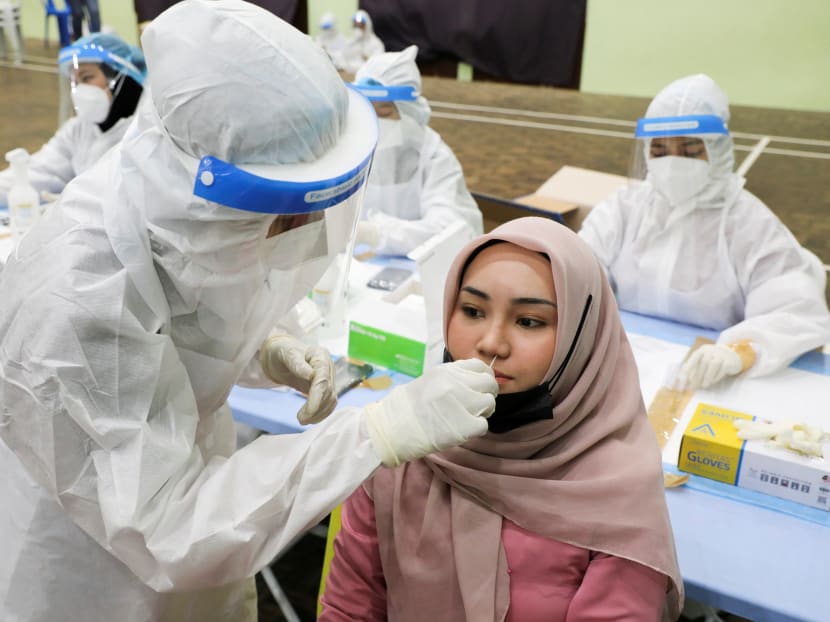 A medical worker collects a swab sample from a woman to be tested for the coronavirus disease in Kuala Lumpur, Malaysia, May 11, 2021.