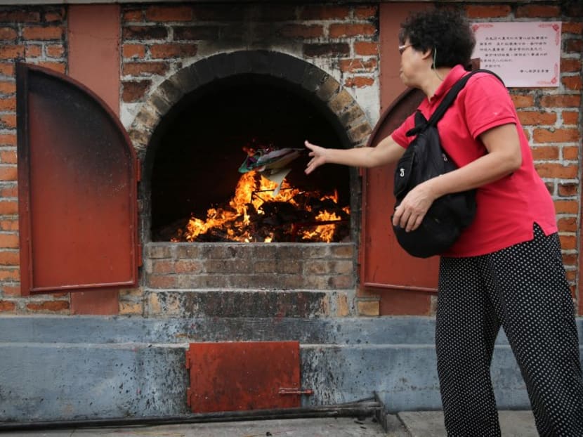 A women burns paper as an offering in Hong Kong. Photo: AFP