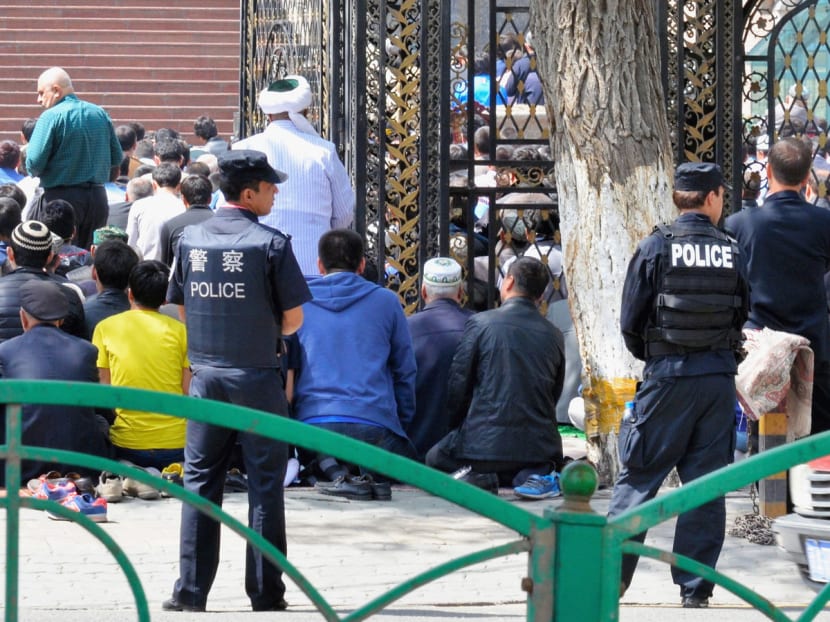 Police officers stand outside a mosque as Uighur Muslims gather for 'Salat' Friday prayer for the first time after a bomb explosion in Urumqi, Xinjiang, China, on May 2, 2014. Photo: Bloomberg