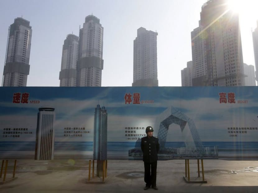 A security guard stands next to an advertising board in front of a residential compound under construction in Wuhan, Hubei province. Reuters file photo