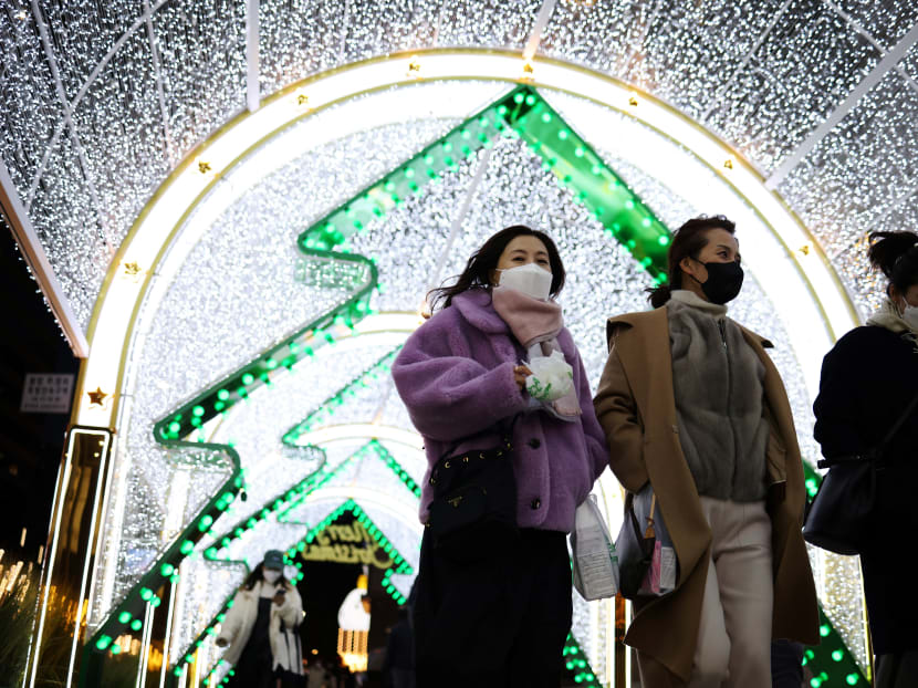 Women wearing masks to prevent contracting Covid-19 walk under a Christmas illumination at a shopping district in central Seoul, South Korea on Dec 1, 2021.