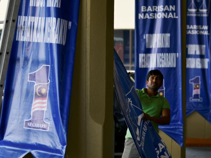 A worker tears down a Barisan Nasional flag at Putra World Trade Centre (PWTC) in Kuala Lumpur on Thursday (May 10).