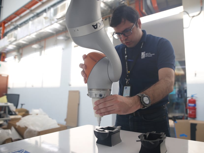 A*Star’s Multi-Modal robot with artificial intelligence being taught by a scientist to glue items on Friday (May 4). The Multi-Modal robot is a robotic platform with the intelligence and ability to recognise speech-activated commands, as well as learn tasks from casual learning.