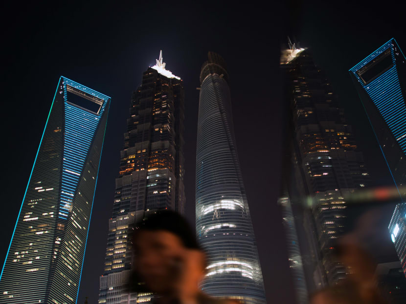 This photo taken on August 21, 2014 in Shanghai shows a woman walking on a bridge in front of Shanghai's skyscrapers and its reflections. AFP file photo