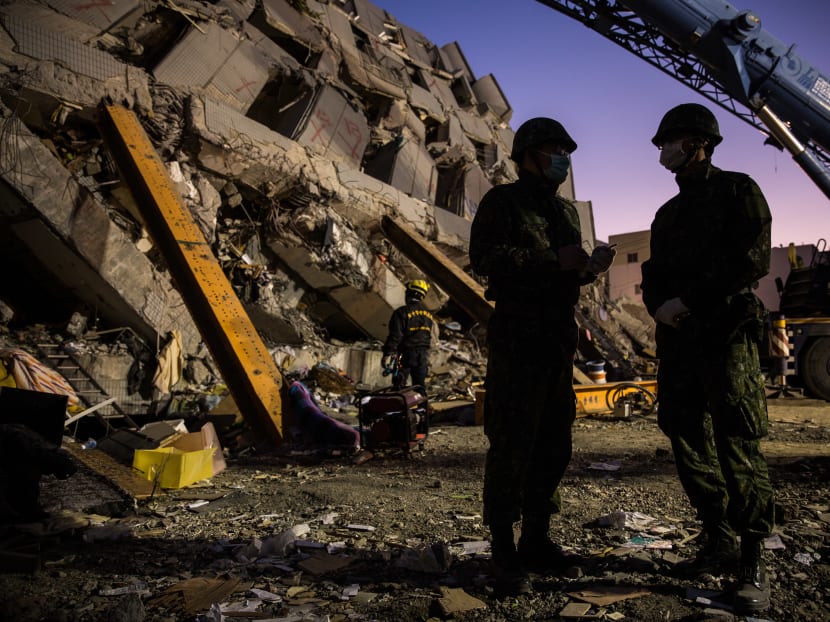 Rescue workers speak as they look for survivors in the remains of a collapsed building in the southern Taiwanese city of Tainan early on Feb 8, 2016. Photo: AFP