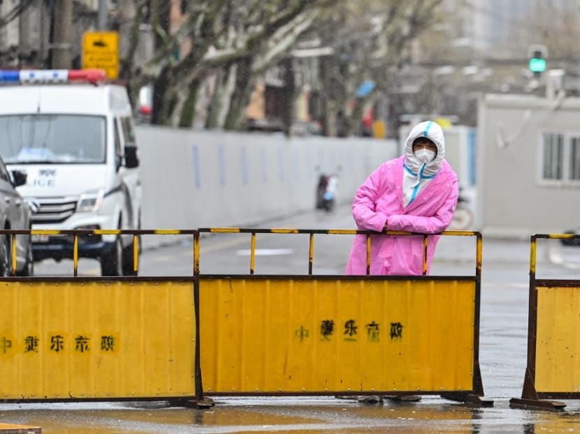A worker wearing protective gear stands next to barriers placed to close off streets around a locked down neighbourhood after the detection of new cases of Covid-19 in the Huangpu district of Shanghai on March 21, 2022.