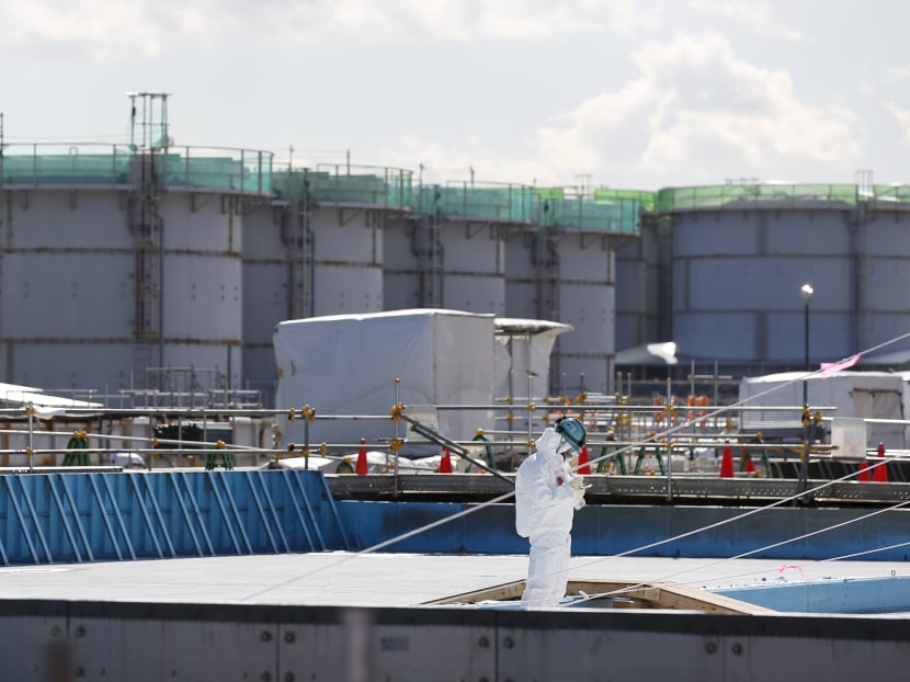 A worker in a protective suit and mask, taking notes in front of storage tanks for radioactive water at tsunami-crippled Fukushima Daiichi nuclear power plant in Okuma town,  Japan in Feb 10, 2016. Photo: Reuters