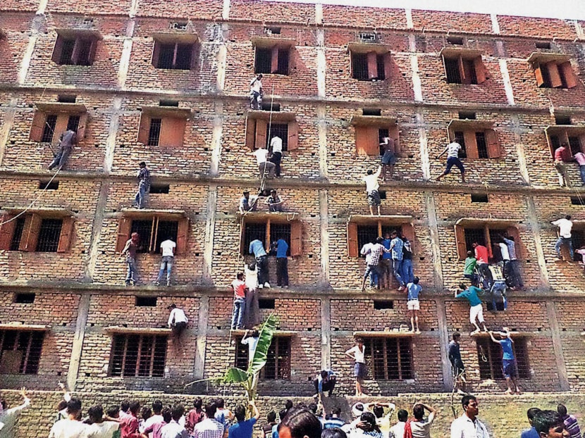 In this Wednesday, March 18, 2015 photo, Indians climb the wall of a building to help students appearing in an examination in Hajipur, in the eastern Indian state of Bihar. Photo: AP