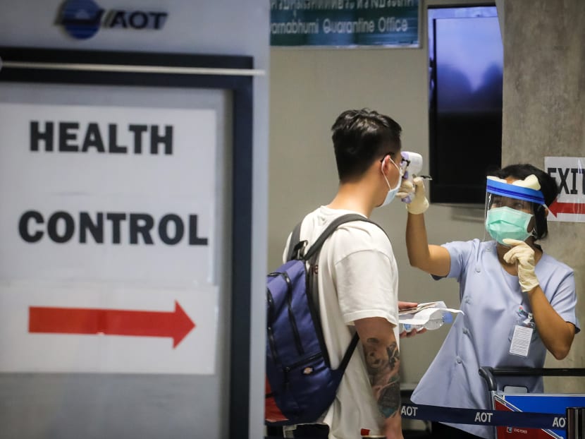 A health official checks the temperature of an incoming passenger during a health assessment at a checkpoint for people flying in from a list of countries and territories that include China, Hong Kong, Macau, South Korea, Iran and Italy, as a precautionary measure against the spread of the Covid-19 coronavirus at Suvarnabhumi Airport in Bangkok on March 9, 2020.