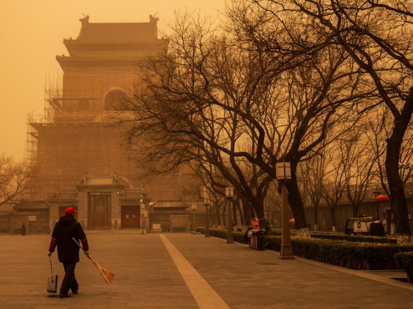 A person walks with a broom and dustpan during morning rush hour as Beijing, China, is hit by a sandstorm on March 15, 2021.