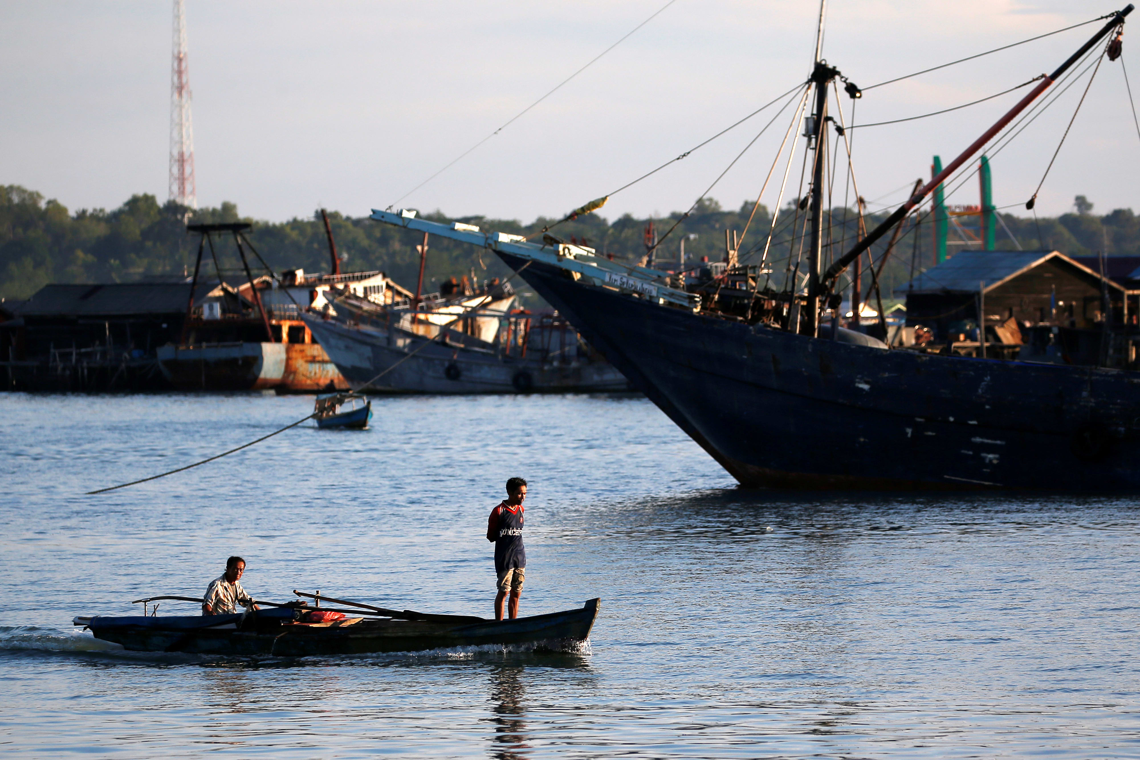 A man stands as he travels on a wooden boat near a port in Tanjung Pinang, on the island of Bintan, Indonesia on June 15, 2019. 