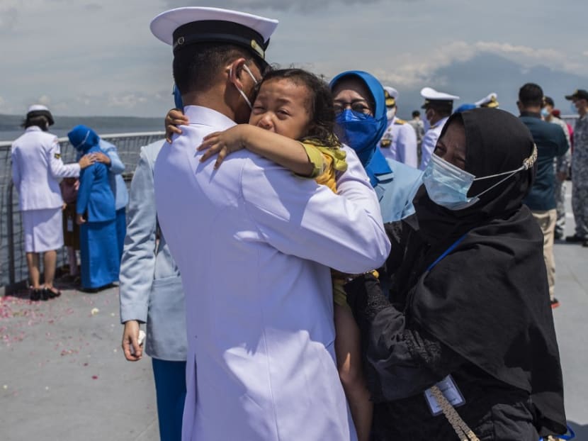 A naval officer hugs a child during a remembrance ceremony for the crew of the Indonesian navy submarine KRI Nanggala that sank on April 21 during a training exercise, on the deck of the hospital ship KRI Dr. Soeharso off the coast of Bali on April 30, 2021.