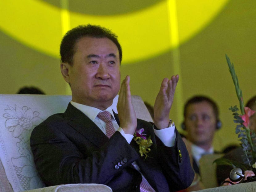 In this file photo, Wanda Chairman Wang Jianlin applauds in front of the logo for Dalian Wanda Group during an event in Beijing. Photo: AP
