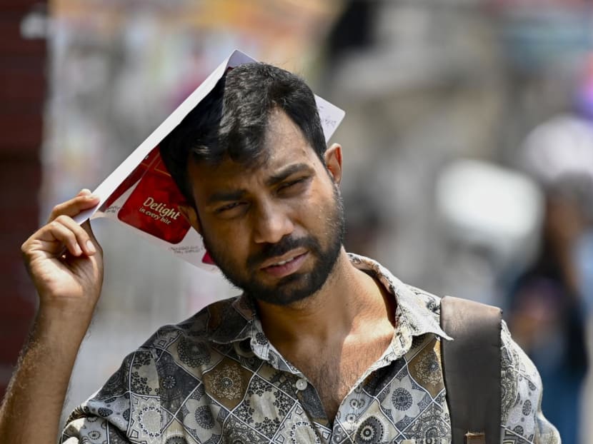A man uses a piece of paper to shelter from sun during a heatwave in Dhaka on June 6, 2023.