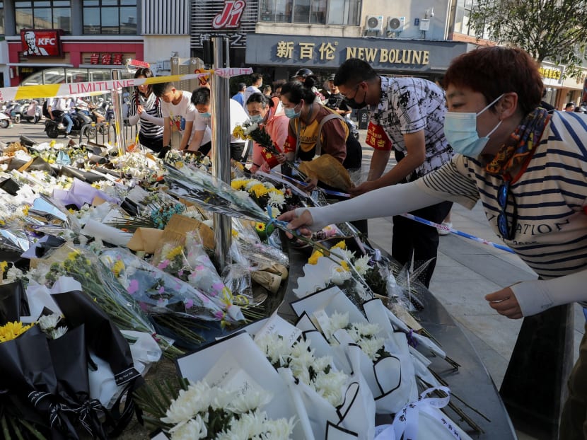 Volunteers arrange flowers at the site of a stabbing which left 6 people dead and 14 wounded, in Anqing, in China's eastern Anhui province on June 6, 2021.