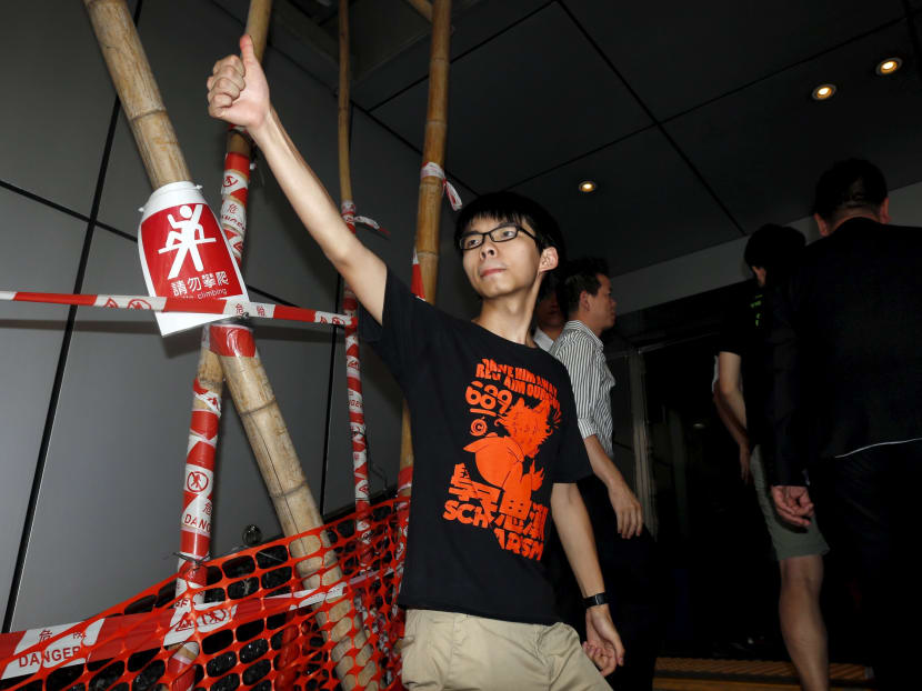 Student leader Joshua Wong shows a thumbs up to his supporters as he walks into a police station in Hong Kong, China, July 14, 2015. Photo: REUTERS