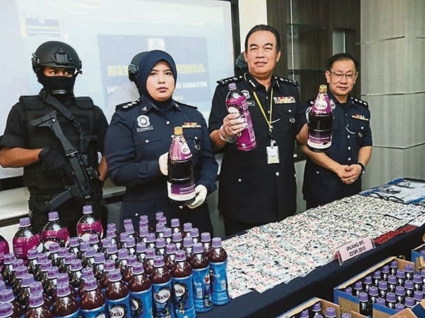 Mr Mohd Dzuraidi Ibrahim, second from right, shows bottles of the drug-laced drinks. Photo: Malay Mail Online