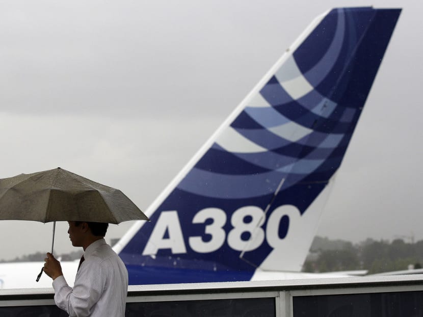 A visitor stands in the rain near an Airbus SAS A380 airplane during the Farnborough International Airshow in Farnborough, UK. Photo: Bloomberg