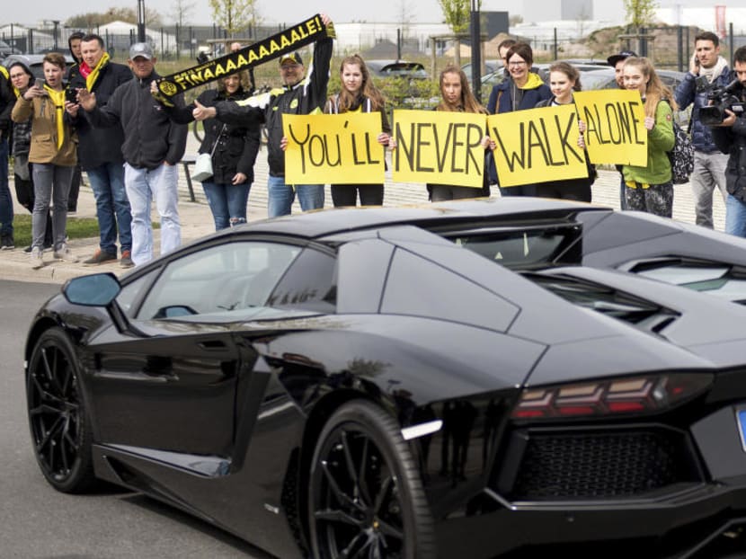 Dortmund fans hold posters proclaiming 'You'll never walk alone' when Dortmund player Pierre-Emerick Aubameyang leaves the training ground of the team in Dortmund on Wednesday (April 12), the day after the team bus was damaged in an explosion which injured a player and a police officer. PHOTO: AP