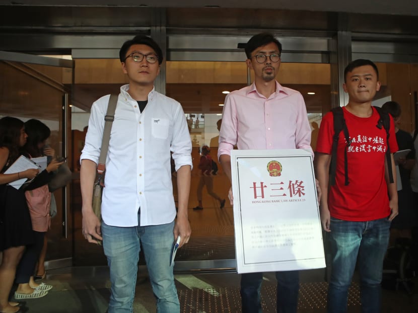 Three high-profile HK localist candidates, from left, Edward Leung of Hong Kong Indigenous, Avery Ng and Chan Tak-cheung from League of Social Democrats, hold a mock copy of controversial, proposed anti-subversion legislation outside a court in Hong Kong. Photo: AP