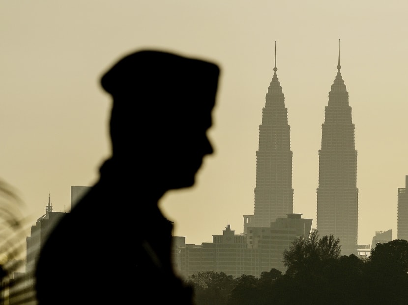 A private security guard walks past as the sun rises over Malaysia's iconic Twin towers in Kuala Lumpur on Jan 8, 2016. Photo: AFP