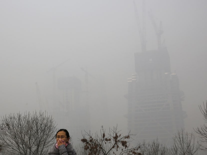 A woman breathes through a cloth in Beijing, which issued its highest smog alert of the year last Sunday. Local experts say China should do more to fight carbon-dioxide pollution. Photo: AP