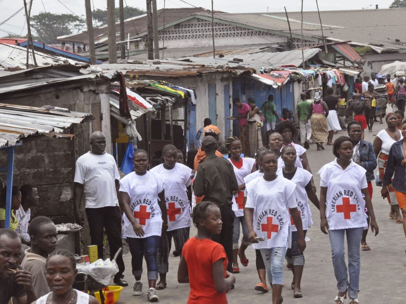 Red Cross workers walk through a section of West Point, an area that has been hit hard by the Ebola virus, with residents not allowed to leave as government forces clamp down on movement to prevent the spread of Ebola, in  Monrovia, Liberia, Aug 27, 2014  Photo: AP