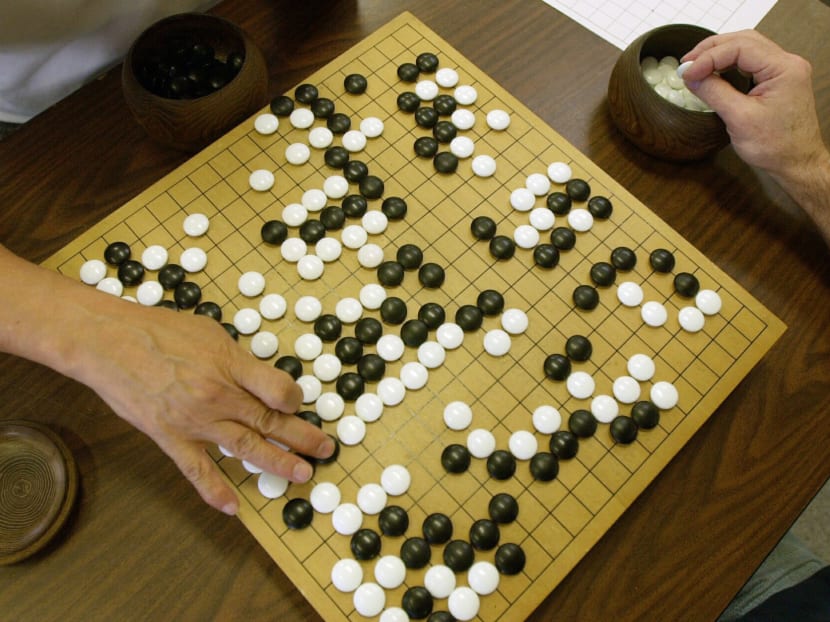 A player places a black stone while his opponent waits to place a white one as they play Go, a game of strategy. Photo: AP