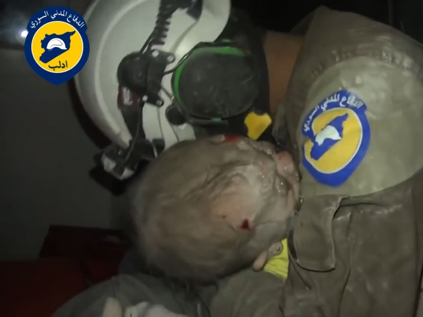 A handout picture released by the Syrian civil defence in Idlib shows an unidentified volunteer cradling four-month-old Wahida after she was rescued from under the rubble of a building following a reported air strike on the rebel-held northwestern city of Idlib on September 29, 2016.  Photo via AFP