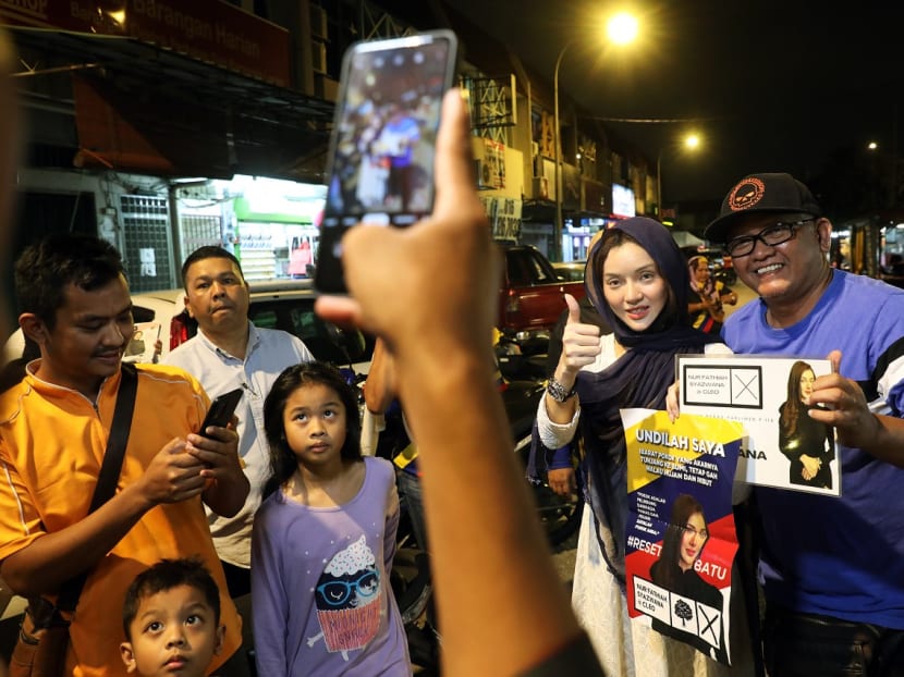 Ms Nur Fathiah Syazwana, an independent candidate contesting the Batu parliamentary seat in Malaysia’s 15th General Election, pose for photos with customers at a night market in Batu on Nov 16, 2022.