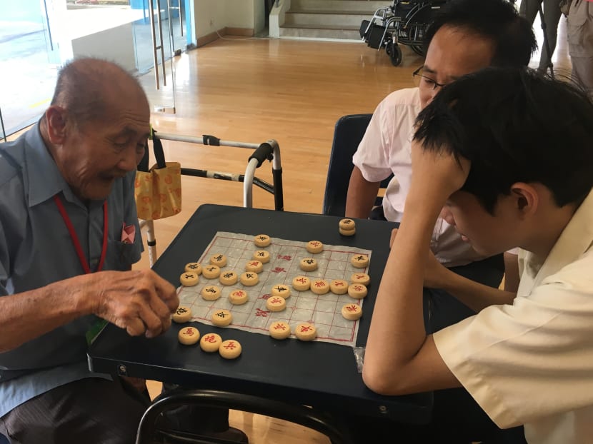A resident from St Luke's Eldercare Centre plays Chinese chess with a student from Fajar Secondary School, at the school's annual Inter-Generational Games on October 26, 2017.