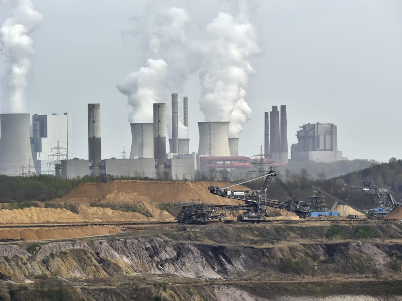 Giant machines dig for brown coal at the open-cast mining Garzweiler in front of a smoking power plant near the city of Grevenbroich in western Germany. Photo: AP