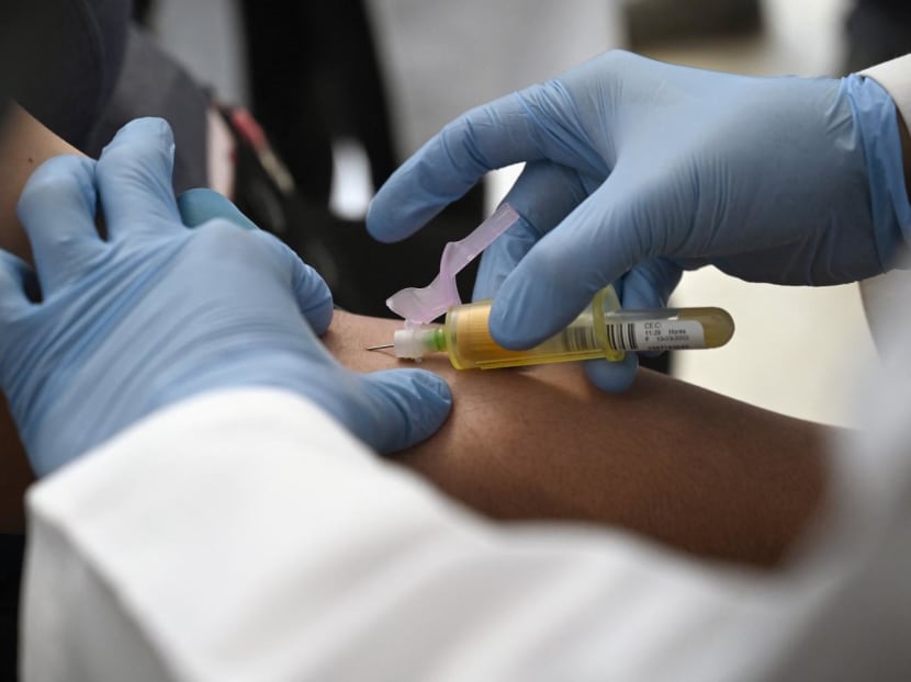A technician extracts blood from a patient for an HIV test.