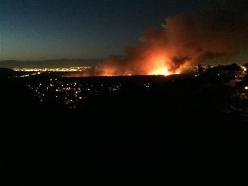 A brush fire that broke out Saturday evening, April 18, 2015 burns in the Dam Prado Dam Flood Control Basin north of the city of Corona, Calif. Photo: AP