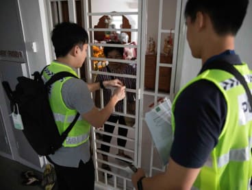 Police officers helping a resident at Block 154 Gangsa Road, while checking to see if all residents have been evacuated.