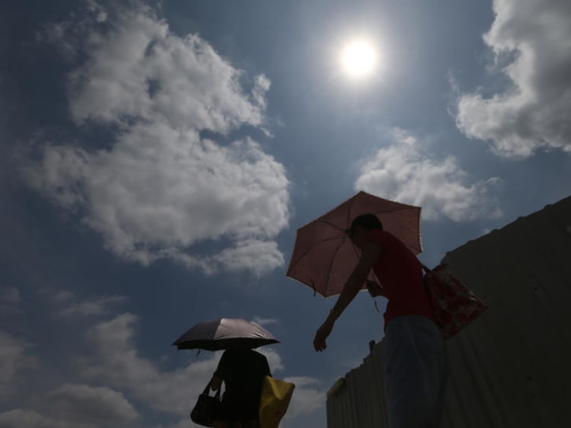 Pedestrians holding up umbrellas for shelter from the hot sun in Singapore. TODAY file photo
