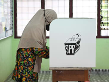 A woman casts her vote at a polling station during the 15th general election in Bera, Malaysia's Pahang state on Nov 19, 2022.
