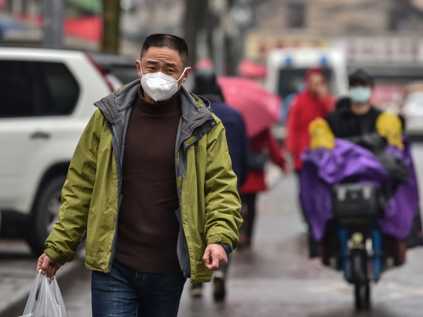 People wearing facemasks to help stop the spread of a deadly virus which began in the city, walk in front of the Wuhan Fifth Hospital in Wuhan in China's central Hubei province on Jan 24, 2020. China sealed off millions more people near the epicentre of a virus outbreak on January 24, shutting down public transport in an eighth city in an unprecedented quarantine effort.