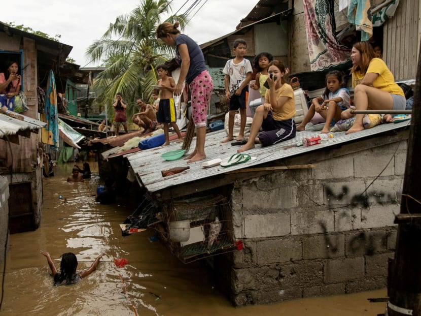 Residents wait on the roof of their homes for the flooding to subside after Super Typhoon Noru, in San Miguel, Bulacan province, Philippines on Sept 26, 2022. 