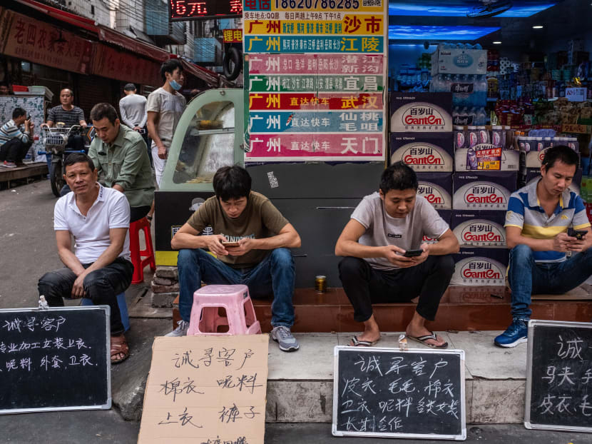 Employees from a garment factory sit behind signs that say ''Looking for customers'' in Chinese, in Guangzhou. The author says China could rethink its practice of setting GDP growth targets.