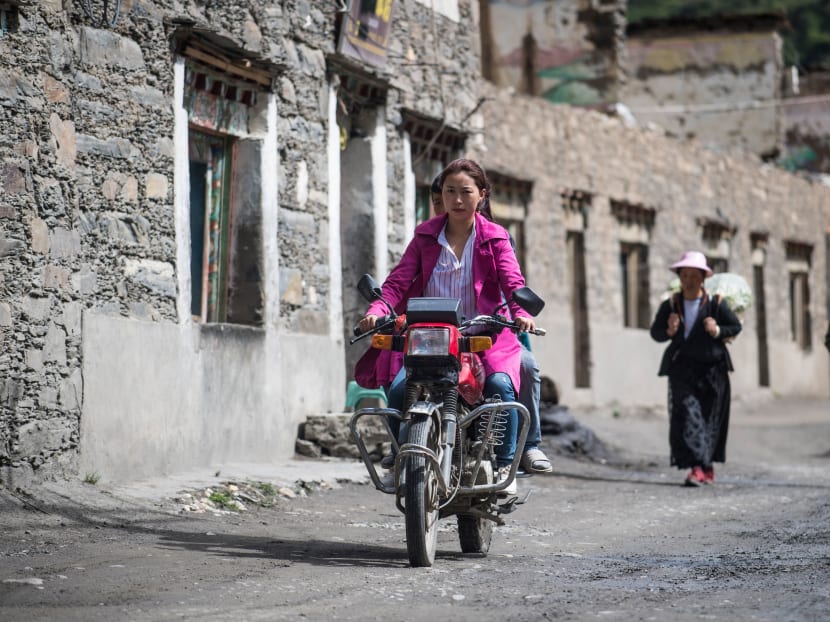 A woman riding a motorcycle on a street in Zhaba in the valley of the Yalong River in Daofu County of the Garze Tibetan Autonomous Prefecture. Photo: AFP