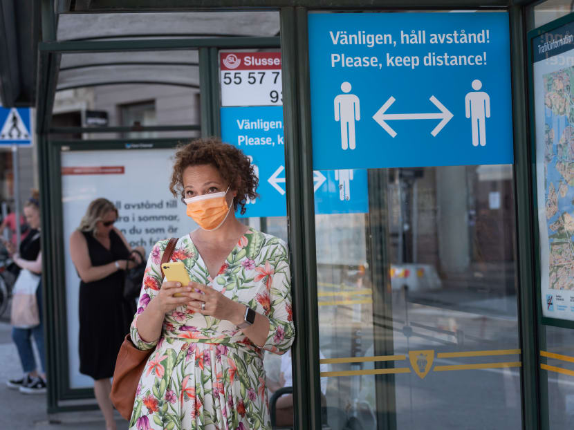 A woman wears a face mask as she waits at a bus stop with an information sign asking people to keep social distance due to the Covid-19 pandemic on June 26, 2020 in Stockholm, Sweden. A woman wears a face mask as she waits at a bus stop with an information sign asking people to keep social distance due to the Covid-19 pandemic on June 26, 2020 in Stockholm, Sweden.