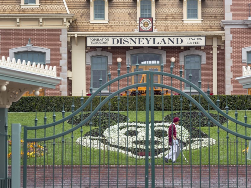 An employee cleans the grounds behind the closed gates of Disneyland Park in Anaheim, California.