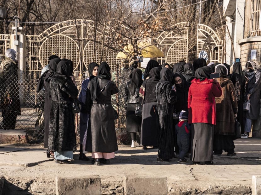 Afghan female university students stop by Taliban security personnel stand next to a university in Kabul on Dec 21, 2022. Afghan female university students stop by Taliban security personnel stand next to a university in Kabul on Dec 21, 2022.