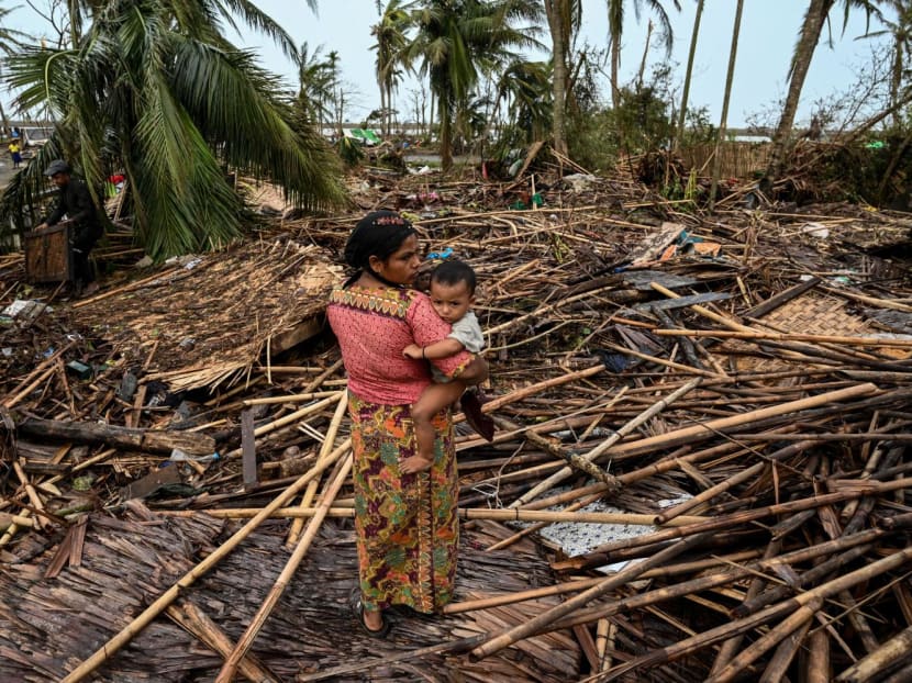  A Rohingya woman carries her baby next to her destroyed house at Basara refugee camp in Sittwe, Myanmar, on May 16, 2023, after Cyclone Mocha made a landfall.