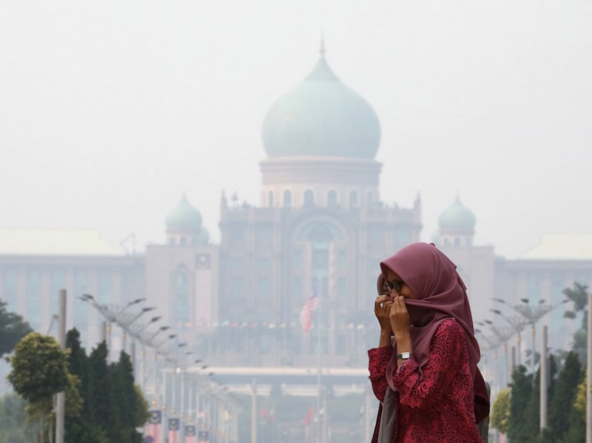 A woman covers her face with a scarf in front of the Prime Minister’s Office, which is shrouded in haze, in Putrajaya, Sept 17, 2019.