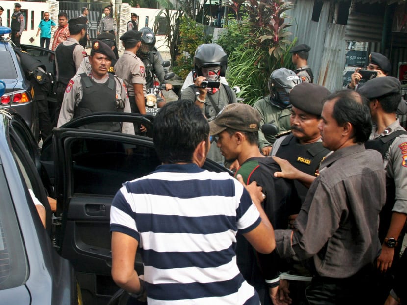 Police escorting a man who was arrested in Tegal, Indonesia, on Jan 15, last year, over links to an attack by the IS in Jakarta. Since then the country has suffered a string of IS-inspired attacks. Photo: Reuters